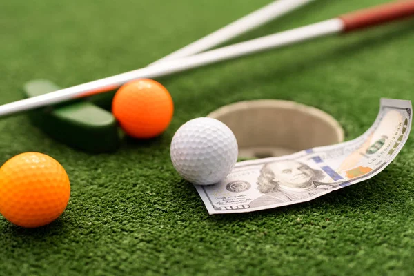 Money, mini golf balls on grass. Concept of sports bet.