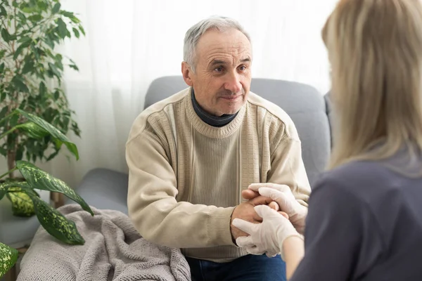 Kind female doctor embracing encouraging senior male patient in hospital. Happy healthy older man and his physician enjoying talking at nursing home. Elderly medical health care concept