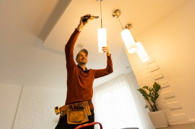 Apartmanın içine elektrik lambaları döşeyen elektrik işçisi. İnşaat dekorasyonu kavramı