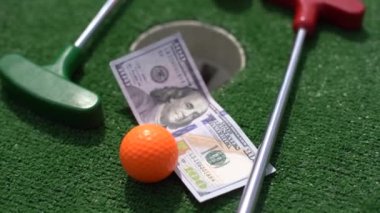 Mini golf sopası, top ve para yapay çimlerin üzerinde..