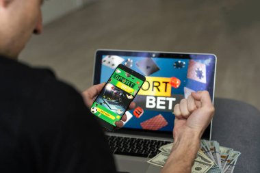 Adam dizüstü bilgisayarında futbol maçı izliyor, favori takımı için tezahürat yapıyor, bahisçilerin internet sitesinde bahis oynuyor..