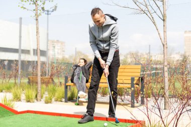 Bir adam mini golf oynamak için çarpışma yerine gider..