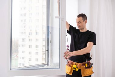 Eldivenlerde uzman. PVC pencerelerini tornavidayla kapatıyor. Plastik pencere onarımı ve bakım konsepti. Yüksek kalite fotoğraf