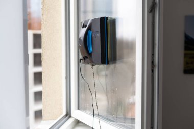 Bir cam temizleyici robot, çok katlı binaların arka planında cam yıkıyor..