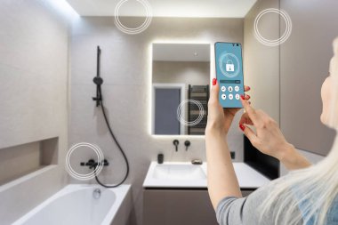 Akıllı ev teknolojisi, akıllı telefon uygulamasındaki IoT İnternet arayüzü modern apartman içindeki nesnelere bağlı ekran, uzaktan kumanda olarak kadın tutucu aygıtı.