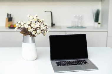 Social media culinary concept, front view of laptop and utensils standing on the modern kitchen countertop.