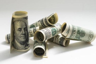 roles dollar notes in front of white background.