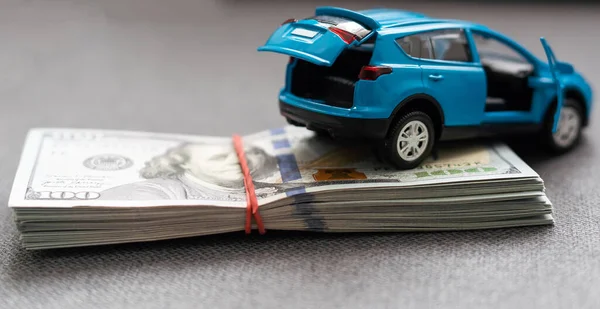 A toy car and banknotes lie, the cost of operating a car