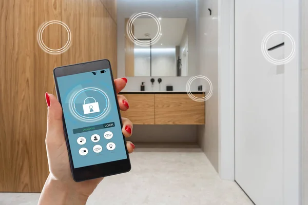 stock image man hand holding phone with app smart home in room house.