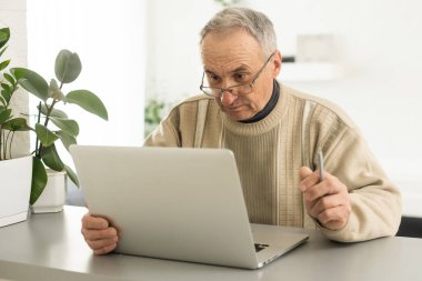 Laptop kullanan akıllı, olgun, profesyonel bir adam. Orta yaşlı yetişkin iş adamı, orta yaşlı uzaktan kumandalı girişimci ya da online daktilo yazmayı öğreniyor