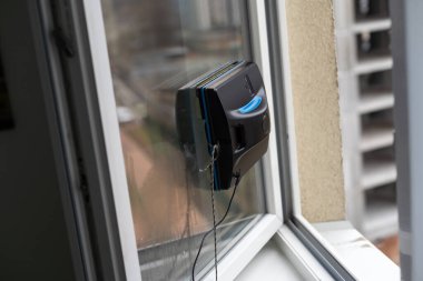 Bir cam temizleyici robot, çok katlı binaların arka planında cam yıkıyor..