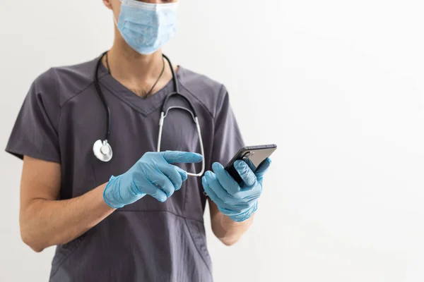 男性医師男性は 病院の使用で白い医療ガウンのスーツ聴診器の仕事を身に着けているショー携帯電話の空白の画面ワークスペースプレーングレーの背景に隔離された領域を示しています 医療の概念 — ストック写真