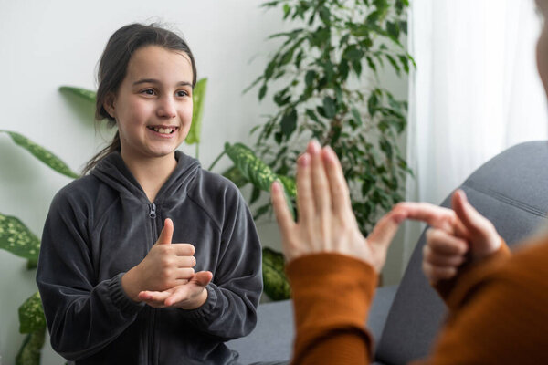 daughter talk with middle aged mother people using sign language, family sitting on armchair side view, teacher teach teenager deaf-mute girl to visual-manual gestures symbols concept image.
