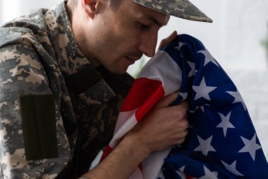 Amerikan bayrağı taşıyan üniformalı ve şapkalı bir asker..