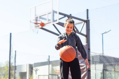 Şehrin arka planında basketbol topu olan bir kız. Sokak basketbolu