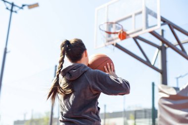 Yaz sezonunda sahada basketbol oynayan bir kız..