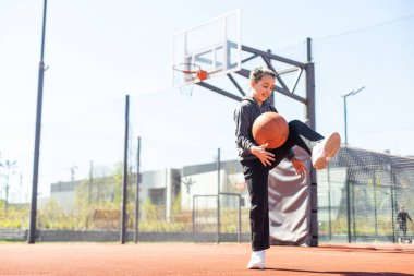 Yaz sezonunda sahada basketbol oynayan bir kız..