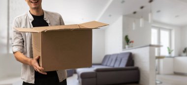 Karton kutu taşıyan hevesli genç adam, evden taşınıyor..