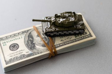 Dolar banknotlarının arka planında oyuncak tankı