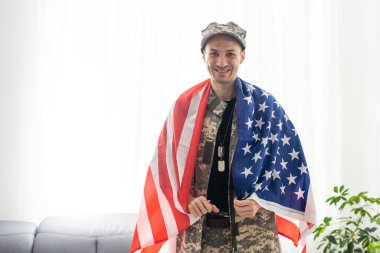 Amerikan bayrağı taşıyan üniformalı ve şapkalı bir asker..