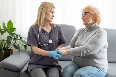 Ev ziyareti sırasında sağlık ziyaretçisi ve yaşlı bir kadın.