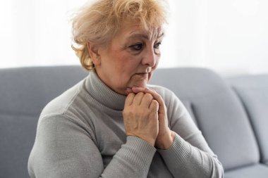 Somurtkan, olgun bir kadın başını katlanmış ellere koyar, mesafeli bakar. Düşüncelere dalmış, yalnız oturan kadını üzmüş. Kafasından yakından çekilmiş bir portre. Zihinsel bozukluk ya da bunama, sağlık problemi kavramı.