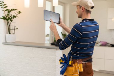 Electrician with tablet indoors, lamp.