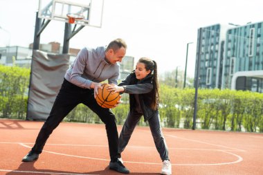 Baba ve kızı sokakta basketbol oynarken.