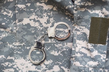 Kamuflaj geçmişinde kelepçe. Metal prangalar izole edildi. Hukuk. Sınırlama. Özgürlük için. - Güvenlik. Polis bilezikleri. Askeri üniforma. Asker tekstil ürünleri. Beneklerin dokusu. Kamuflaj renkleri