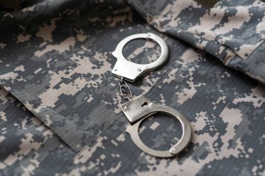 Askeri kamuflaj, kelepçeli. Kavram: Savaş suçlusu, savaş esiri, firariler mahkemesi, vatana ihanet