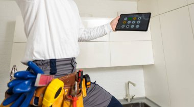 A worker looks at a tablet computer. Master with an electronic tablet in his hands.
