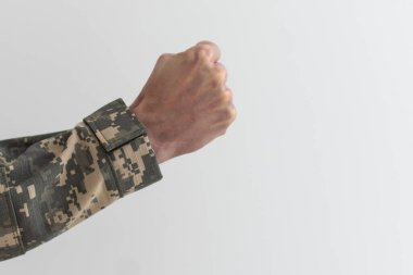 El kamuflajı gri arka planda bir jest olduğunu gösteriyor. Parmaklar bir yumruğa sıkıştı. Orduda jestler donar. Ordu jest dili