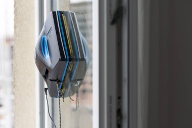 Bir cam temizleyici robot, çok katlı binaların arka planında cam yıkıyor..