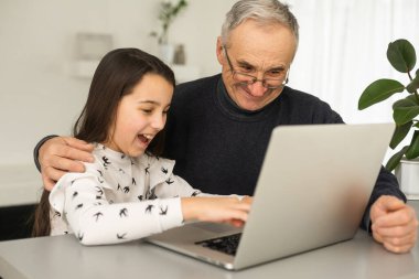 Dedemin ve torunumun dizüstü bilgisayarla ödev yaparken portresi.