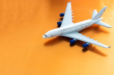Airplane model. White plane on orange background. Travel vacation concept. Summer background. Flat lay, top view, copy space