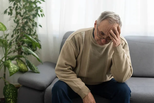 stock image Elderly man with hand on his temple has a headache.