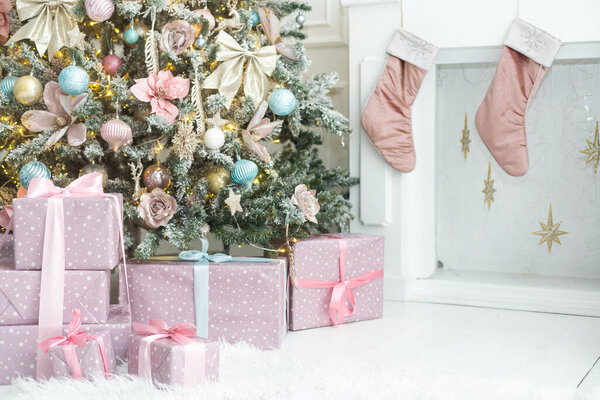 Красивые рождественские подарки под елкой на полу в номере
