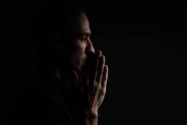 Dua sadık olgun adam yakın çekim, katlanmış içinde ibadet Tanrı'yla baş aşağı ve gözleri dini şevk içinde kapalı eller. Siyah arka plan. Din, inanç, dua ve maneviyat için kavram.