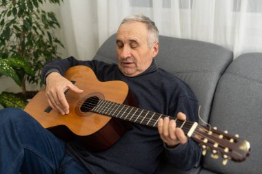 Yaşlı bir adam gitar çalıyor.