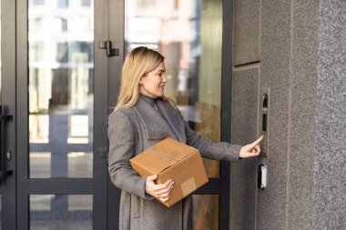 Bina girişinde dahili telefon kullanan kadın