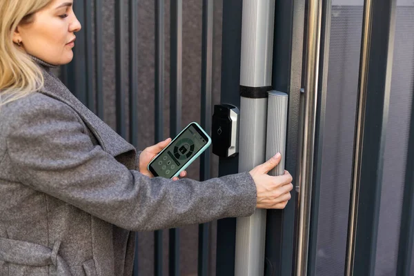 female entering secret key code for getting access and passing building using application on mobile phone, woman pressing buttons on control panel for disarming smart home system.