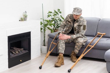 Koltuk değnekli askeri üniformalı asker..