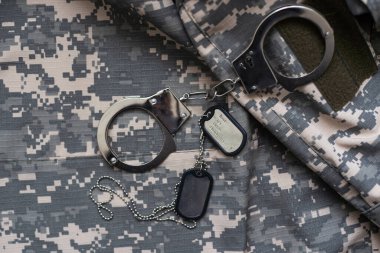 Askeri kamuflaj, kelepçeli. Kavram: Savaş suçlusu, savaş esiri, firariler mahkemesi, vatana ihanet