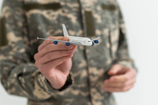 Military Technical Service, Air Force Concept. Hands of a man in uniform holding a silver toy airplane. A middle-aged adult man in a green camouflage uniform. Indoors. Selective Focus. Low key.