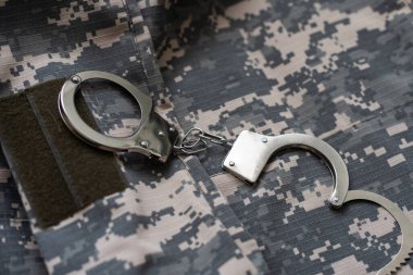Kamuflaj geçmişinde kelepçe. Metal prangalar izole edildi. Hukuk. Sınırlama. Özgürlük için. - Güvenlik. Polis bilezikleri. Askeri üniforma. Asker tekstil ürünleri. Beneklerin dokusu. Kamuflaj renkleri