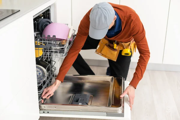 ドライバを使用して特別な服の男またはサービスワーカーは カウンターに取り付けるか 食器洗い機を削除します — ストック写真