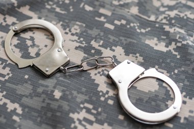 Askeri kamuflaj, kelepçeli. Kavram: Savaş suçlusu, savaş esiri, firariler mahkemesi, vatana ihanet