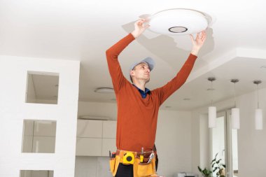 Apartmanın içine elektrik lambaları döşeyen elektrik işçisi. İnşaat dekorasyonu kavramı