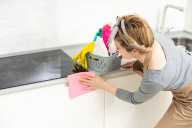 Hafta sonu ödevi. Genç ve güzel bir kadın evdeki rahat oturma odasını temizliyor. Parlak bir odada, ev kıyafetleri ve lastik eldivenler içinde güzel bir kadın.