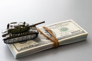 Dolar banknotlarının arka planında oyuncak tankı